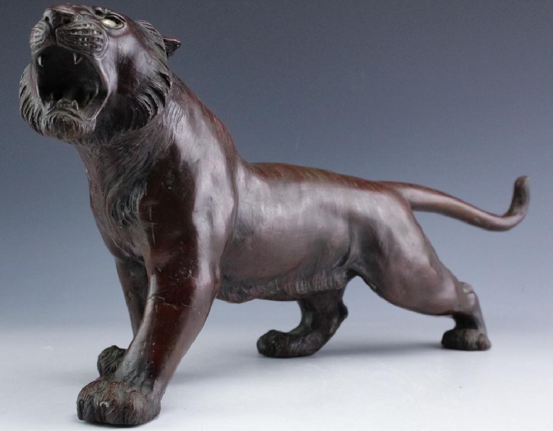 Japanese Meiji Period Bronze Tiger with Glass Eyes: Vintage Japanese bronze sculpture of a tiger. Features the form of a striped tiger with a fierce expression and glass eyes. Character marks on base. Measures 9 1/2" x 19 1/2". Good overall condition w