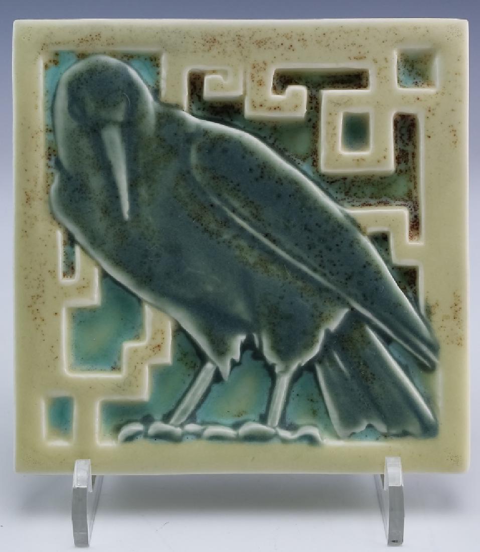 1918 Rookwood Studio Art Pottery Rook Tile Trivet: Circa 1918 Rookwood art pottery trivet. Features the form titled Rook. Depicts a crow like bird rendered in a grayish green in a cream and blue ground. Marked with the Rookwood impressed stamp XVIII 1