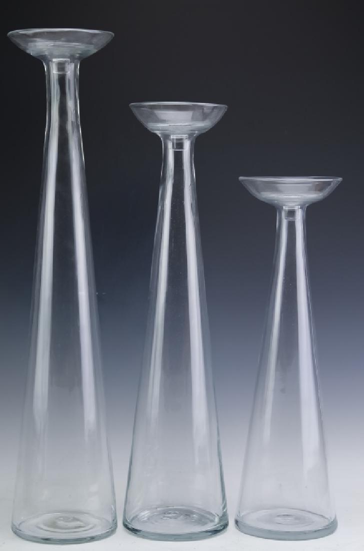 3 Blenko American Art Glass Graduated Floor Vases: Graduated set of three floor vase candleholders by Blenko. Hand crafted of mouth blown glass in "Crystal" Designed by Don Shepherd number 8727 first introduced in the 1987 catalogue. Lot contains 28",