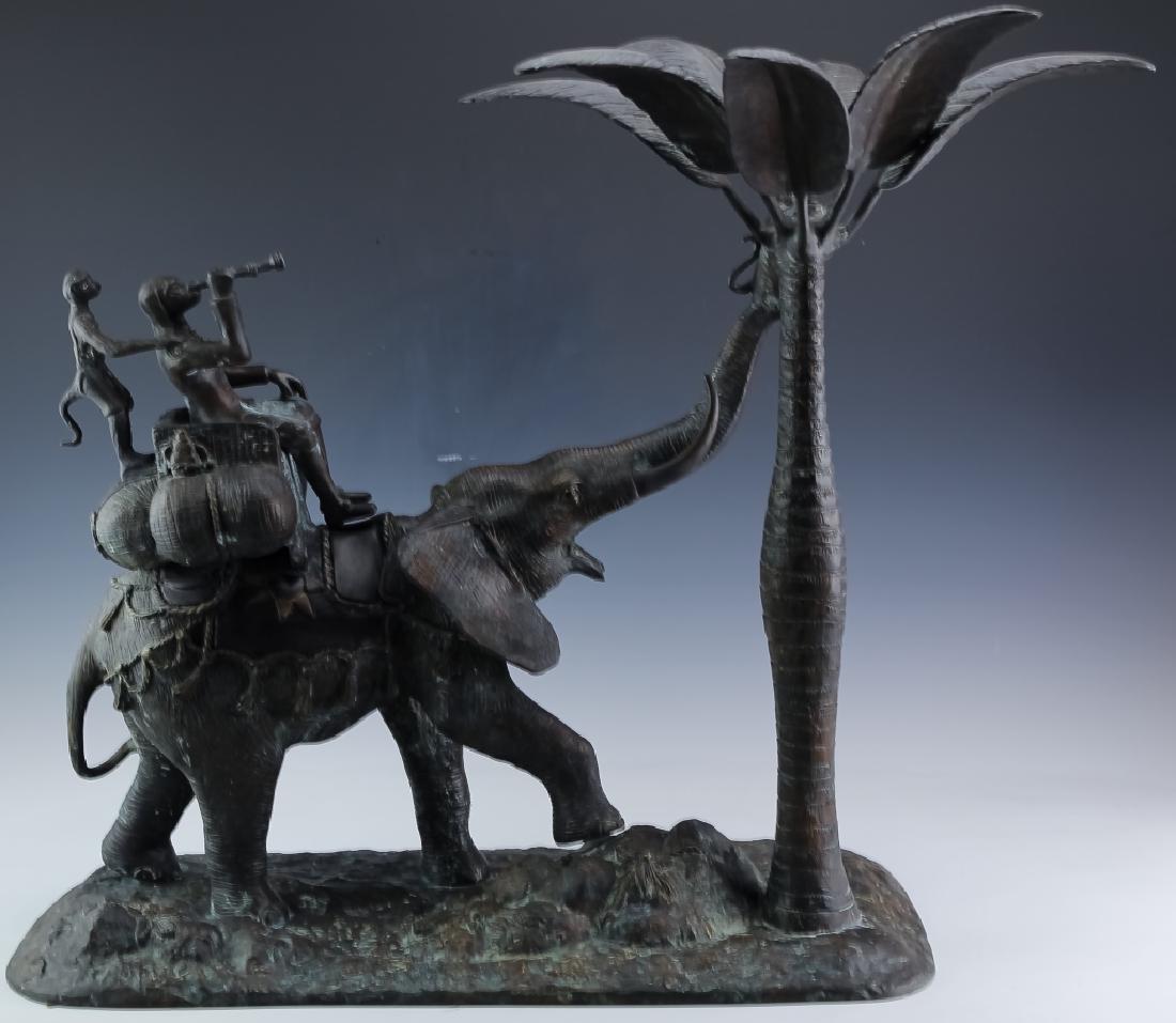 Maitland Smith Elephant Bronze Candlestick Holder: Large Maitland Smith candle stick holder. Crafted of solid cast bronze. Features an elephant with its trunk up and monkeys riding along side of a palm tree. Measures approximately 25" x 24" x 12". Goo