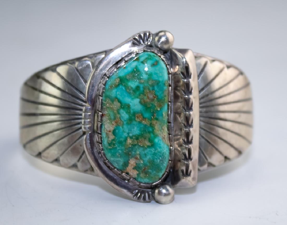 Wilson Padilla Navajo Sterling Turquoise Bracelet: Wilson Padilla Native American Navajo cuff bracelet. Features a large fine gem turquoise cabochon, set in a stamped embellished bezel. Measures 42mm wide. Measures 6 1/2 including gap. Marked Wilson P