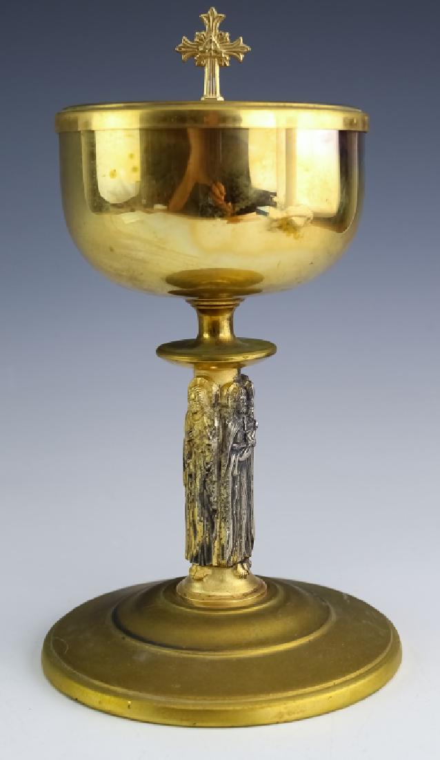 Roman Catholic Gilt Sterling Silver Communion Cup: Roman Catholic sterling silver communion chalice. Features a lidded bowl with gold gilt with a stem consisting of raised saints or angels. Marked Sterling. Weighs 785 grams. Good overall condition wit