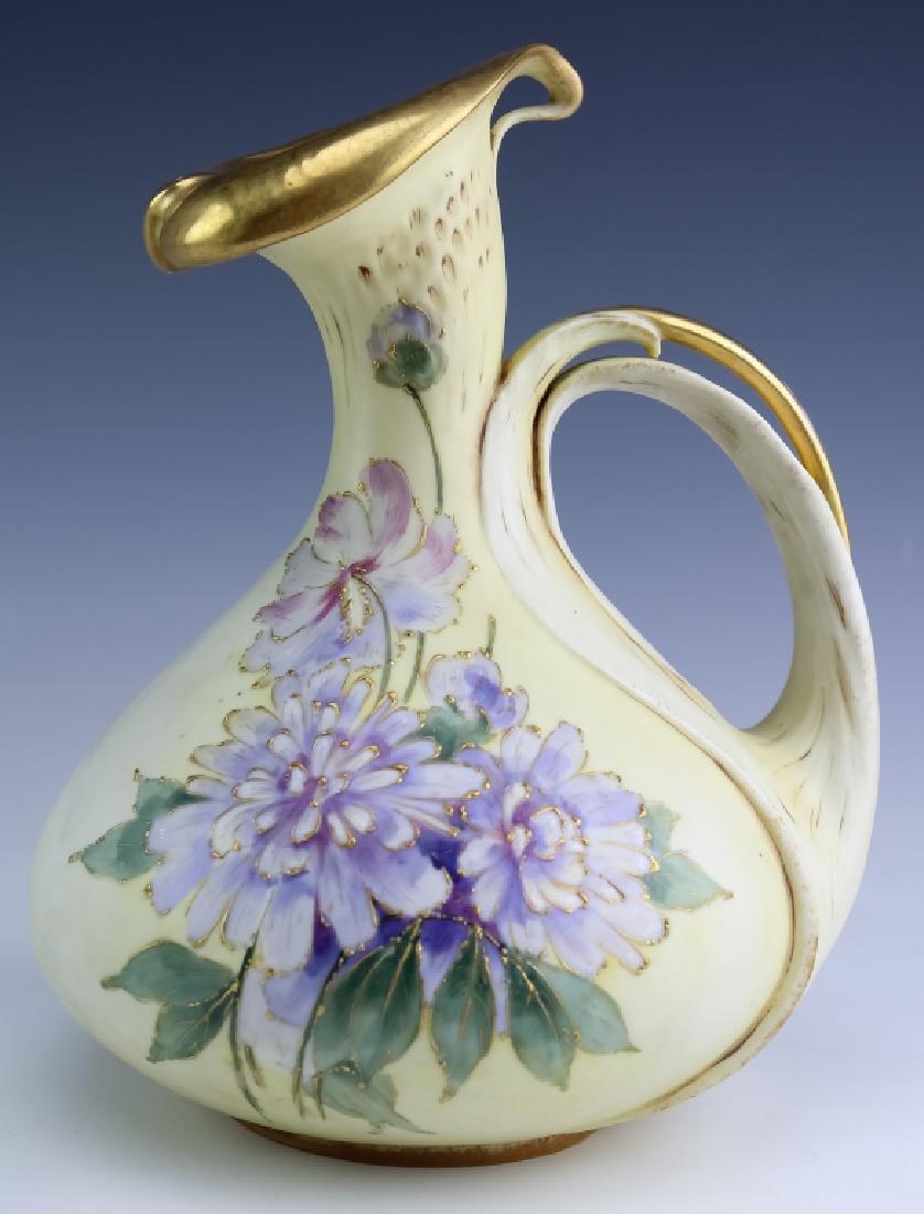Amphora Art Nouveau Art Pottery Gilt Floral Jug: Amphora studio art pottery handled jug. Features a floral form with a gilt gold spout and reticulated handle. Further embellished with hand painted floral decoration. Measures 9" x 7". Marked with imp