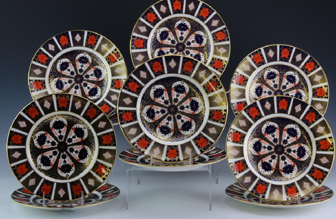 12 Royal Crown Derby Imari Porcelain Dinner Plates: Set of twelve dinner plates by Royal Crown Derby. Crafted of fine quality English porcelain. Imari pattern 1128. Hand painted details with gold gilt highlights. Each plate measures approximately 10 1/