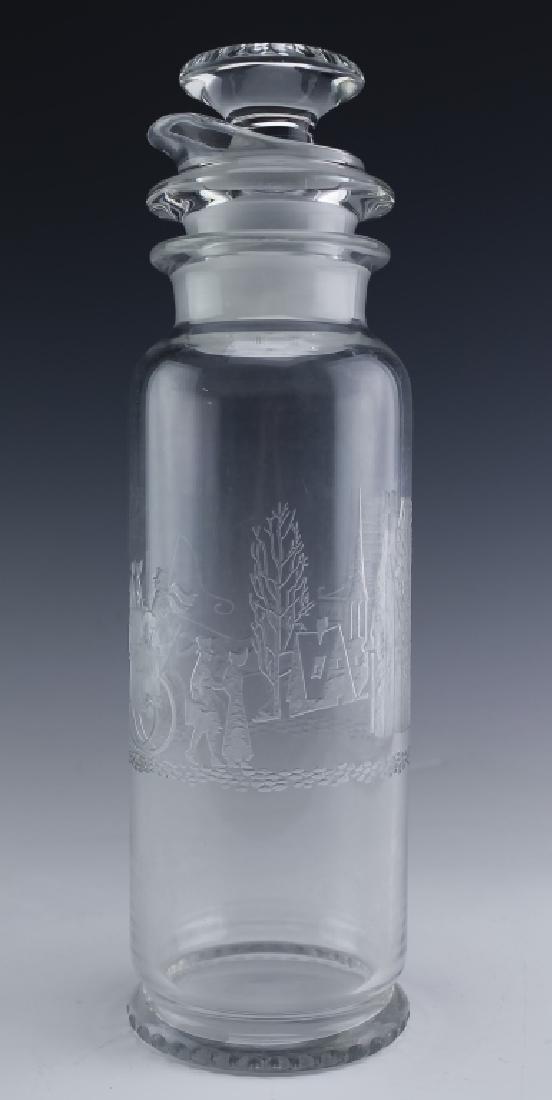 Heisey Glass Tally Ho Decanter Strainer & Stopper: Heisey Glass shaker with strainer. features the Tally Ho pattern with etched scene with buildings and a horse drawn carriage. Comes with stopper and strainer. Measures 12" x 3 1/2". Unsigned. Good ove