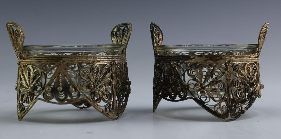 Pair Antique Sterling Silver Filigree Salt Cellars: Pair of antique sterling silver filigree and glass salt cellars. Features a pair of fine wire filigree salt cellars with clear glass liners that fit snuggly in place. Unmarked but tested silver. Measu