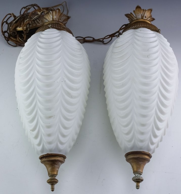 Pair Vintage Opaline Glass Hanging Pendulum Lamps: Pair of vintage hanging lamps. Feature a pair of scalloped white glass shades hanging from brass chains. Lamps measures 18" x 8". Good overall condition with some storage and age related wear to metal