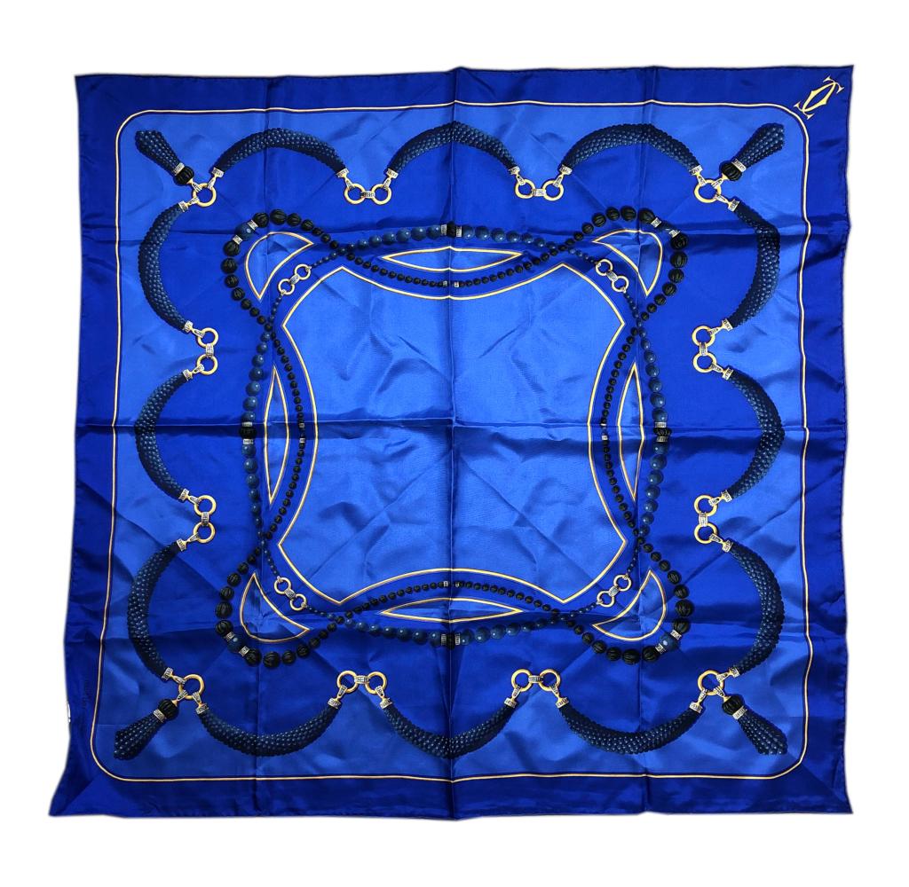 Cartier Must De Cartier Blue French Silk Scarf: Blue Cartier French silk scarf. Sautoir gold and beaded jewel motif. Sewn on MADE IN FRANCE 100% silk tag. Must De Cartier France signature in bottom right corner of scarf. Scarf: 33 in. x 33 in. Good