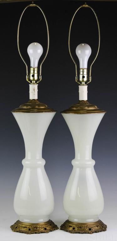 Pair of Fine French Opaline Glass Table Lamps: Pair of fine French glass lamps. Features milky opaline glass bodies with metal mounts. Measures 20" tall and 38" tall overall. Good overall condition with no damage to note. Hill Auction Gallery will