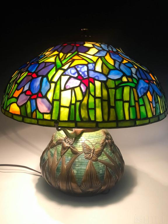 Tiffany Style Patinated Bronze Lily Butterfly Lamp: Tiffany Studios style Lily and Butterfly lamp. Yellow, blue, white and green leaded glass shade and inlaid base. Features bronze lily & butterfly motif. Three light lamp. Good condition with normal ag