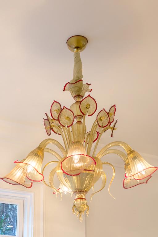6 Arm Murano Art Glass Red Lip Floral Chandelier: Beautiful Murano Italian art glass chandelier. Features Jack-in-the-Pulpit style floral design in gold flecked glass with ruby red lip accents. Six light style with a additional upright florals around