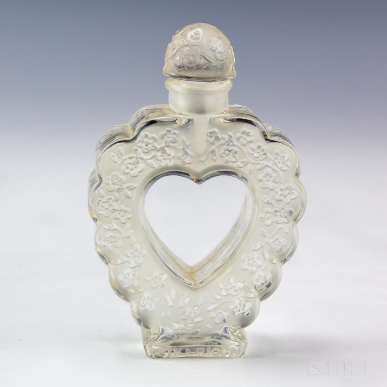Lalique Nina Ricci Coeur Joie Heart Perfume Bottle: Vintage Nina Ricci Coeur Joie crystal heart perfume bottle. Featuring frosted and clear crystal floral hart shaped body with butterfly stopper. Underside of the bottle signed Lalique France. Bottle: 5