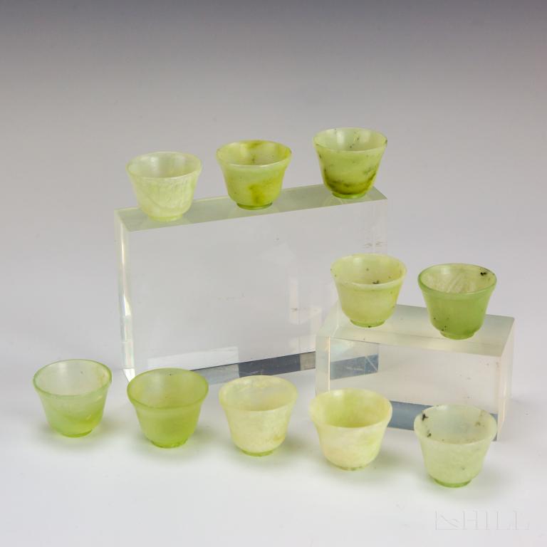 10 Chinese Qing Dynasty Celadon Jade Sake Tea Cups: Set of ten Chinese jade cups. Crafted from light green semi translucent jade with footed base. Measures 1 1/4" x 1 5/8". Good overall condition with minor wear, rim nick to one and crack to one. Hill 