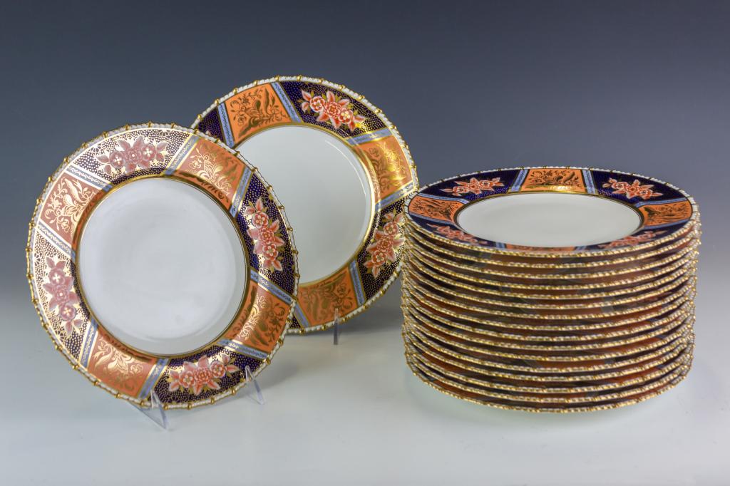 Set 18 Royal Crown Derby Porcelain Dinner Plates: Crafted of fine quality English bone china porcelain. Features an Imari style border with cobalt blue, rust red, peach and periwinkle blue colors with lavish gold gilt accents. Signed with the Royal C