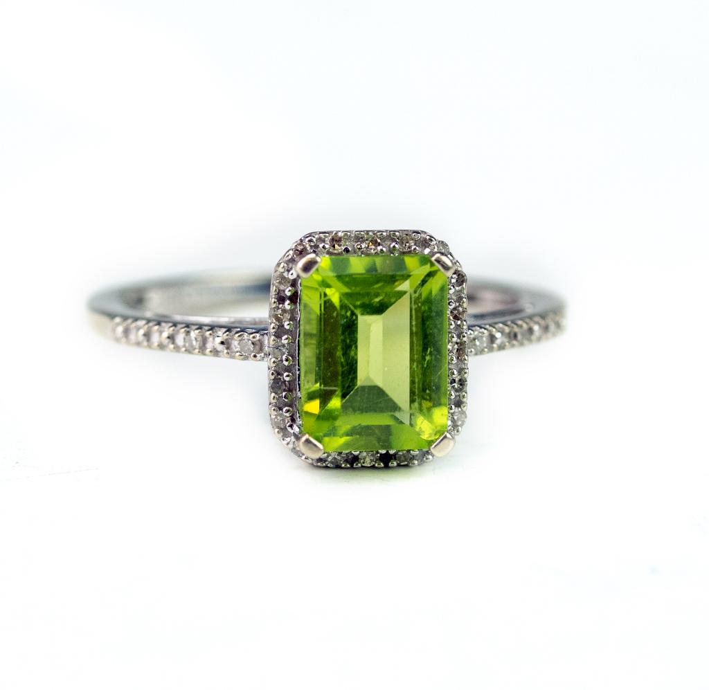 Ladies White Gold Diamond & Peridot Gemstone Ring: Ladies white gold and gemstone ring. Features a green Peridot in a prong setting with accent diamonds flanking it. Total gemstone weight is 1.75 carats. Size 7. Marked 10k. Makers marked P*M. Weighs 2