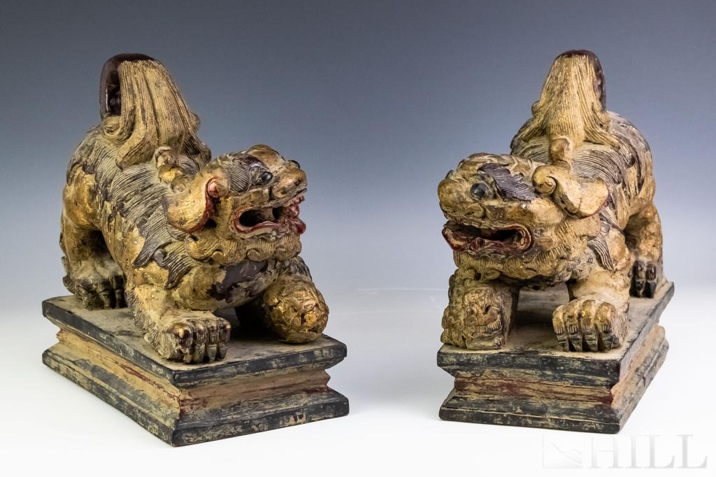 Pair Old Chinese Carved Wood Foo Dog Sculptures: Pair of old Chinese carved wood foo dogs. Features the form of foo dogs on rectangular bases and embellished with polychrome and gold gilt decoration. Measures 11" x 10" x 5 1/2". No apparent markings