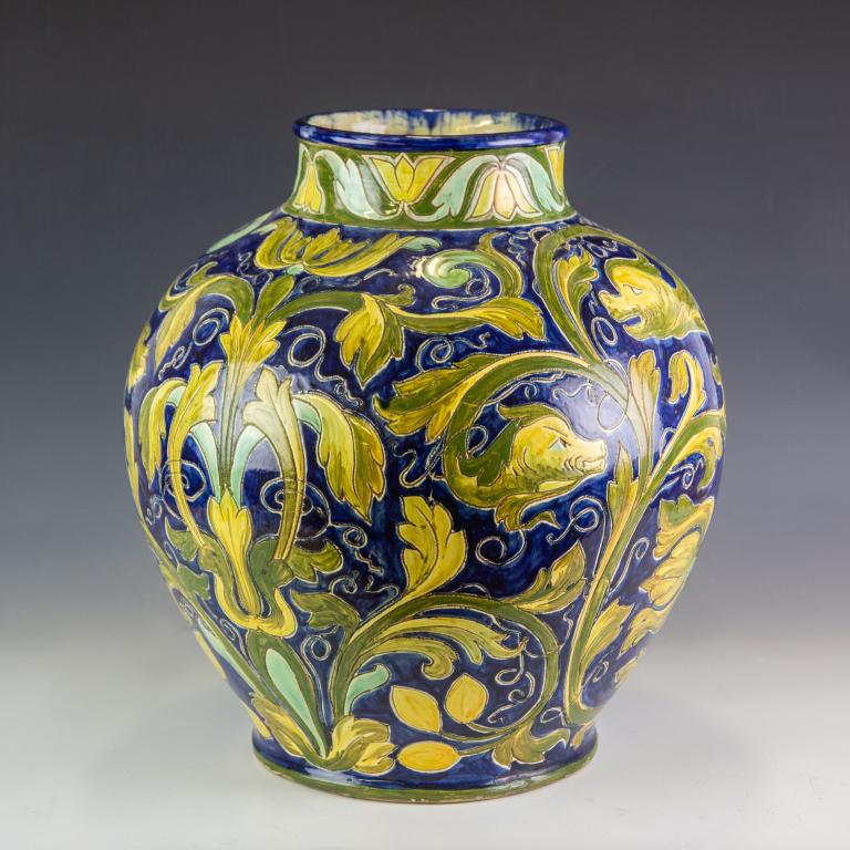 Cassandia Walker Della Robbia English Pottery Vase: Crafted of redware pottery. Hand painted in gorgeous blue and yellow with light green colors. Italian 14th century style with North Wind masks. Signed with the Della Robbia ship mark and the decorator