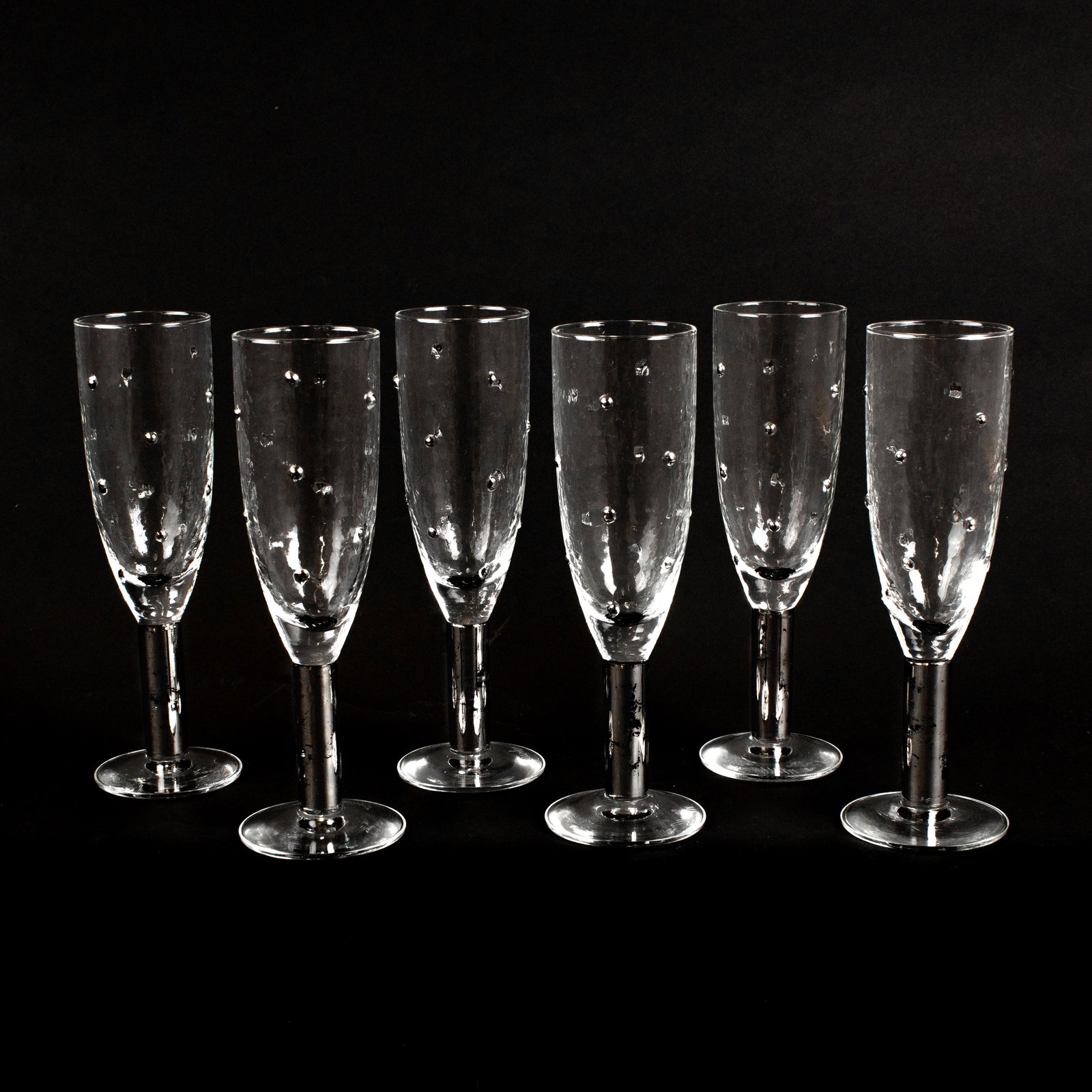 Stephen Smyers Art Glass Fluted Champagne Glasses: Set of six champagne flutes, wine glasses by Stephen Smyers. Features and hand blown Morocco pattern in platinum with flecked stem consistent with artist intent. Signed on base. Measures 8 in. tall. G