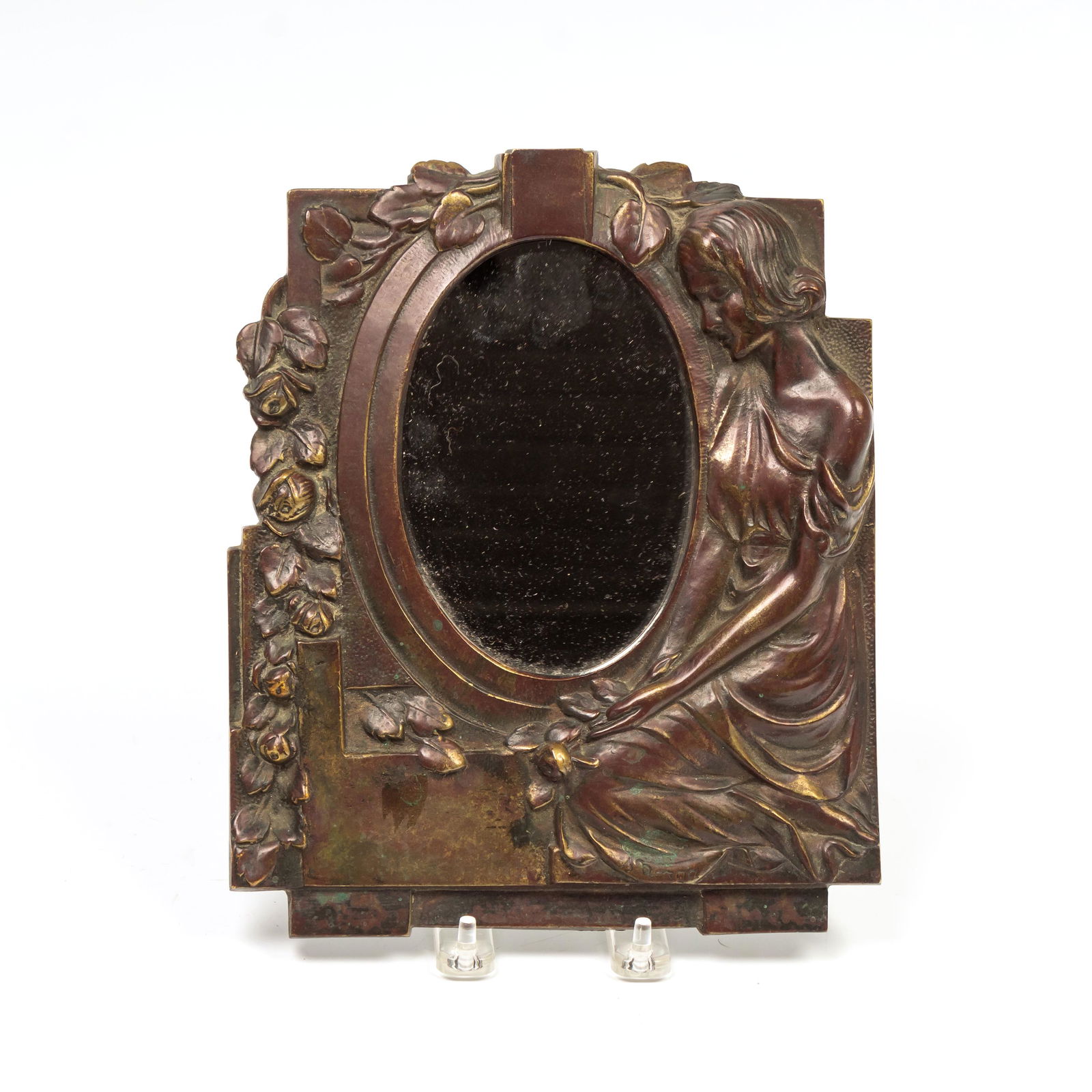 Sylvain Norga 1892-1968 Art Deco Bronze Mirror: Sylvain Norga (Belgian, 1892-1968). A wall mounted hanging mirror featuring the form of a woman. Embellished with roses to one side. Measures 10 in. x 8 1/2 in., with 1/2 in. x 3 1/2 in. mirror. Good