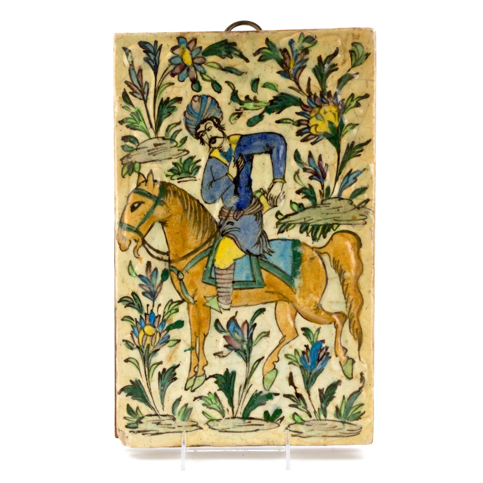 Persian Glazed 14" Molded Qajar Tile Man On Horse: A striking circa Ottoman Period glazed molded Persian Quajar tile depicting a man on horse. Tile is mounted to wood with metal ring for hanging. Measures 14 3/4 in. x 9 1/4 in. x 1 1/2 in. Good condit