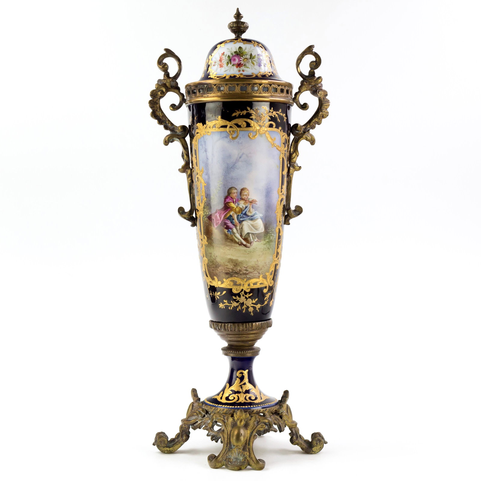 Sevres Style Porcelain Bronze Mounted Urn w/ Lid: Victorian antique Sevres style porcelain lidded urn, mounted in ornate bronze. Featuring cobalt body with transfer and hand painted Romantic figural landscape scenes depicting children and a lovely la