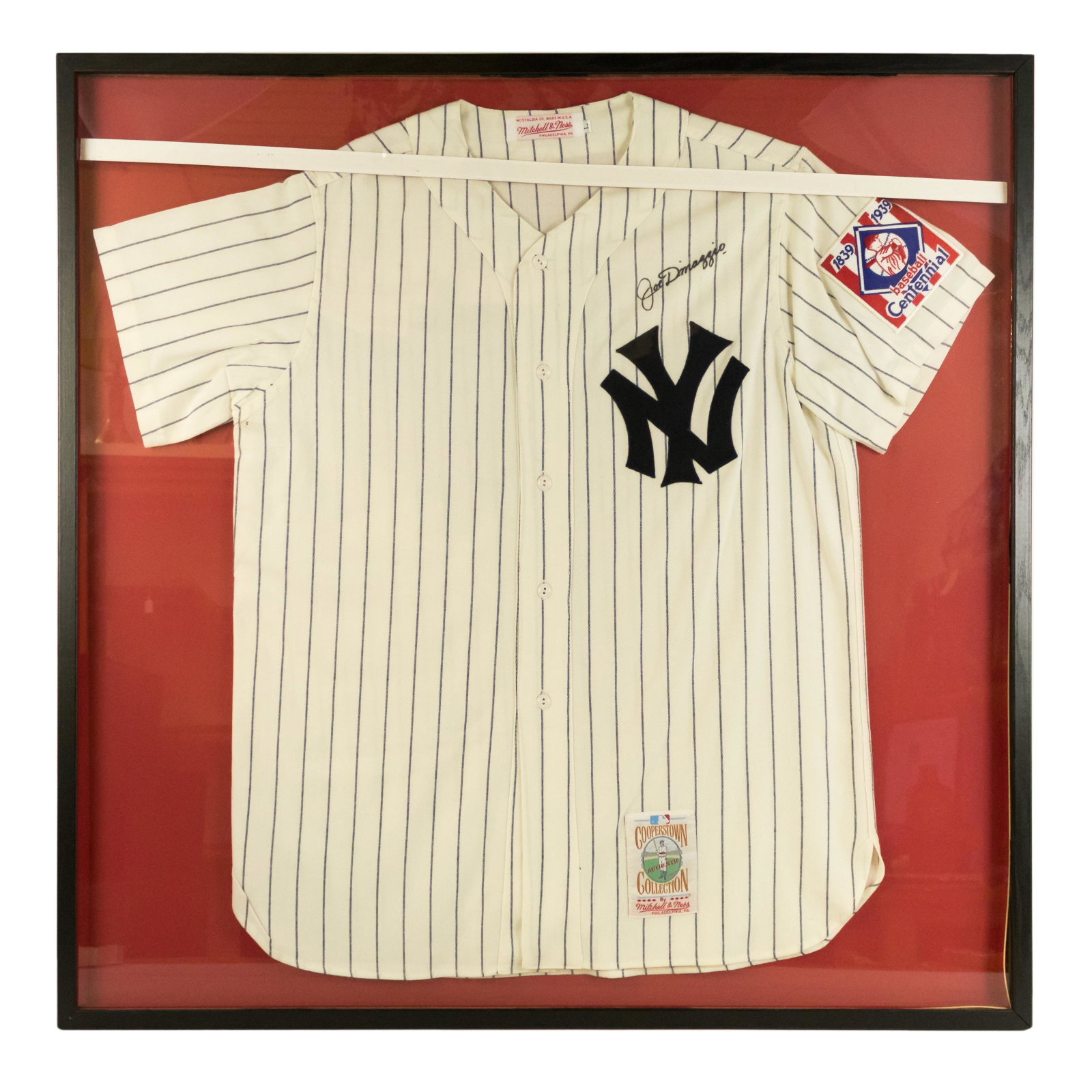 Joe DiMaggio SIGNED New York Yankee Uniform Jersey: An original framed MLB Cooperstown Collection shirt autographed by American Baseball Hall of Fame center fielder Joe DiMaggio (1914–1999), nicknamed "Joltin' Joe" and "The Yankee Clipper," who is wi