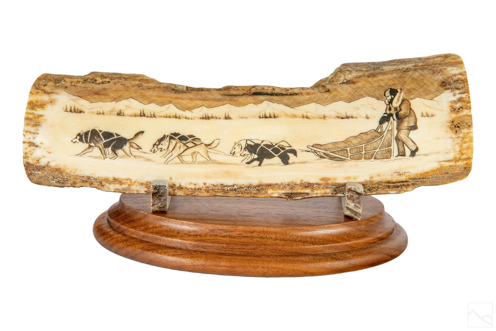 John Majak 20C Alaskan Inuit Iditarod Scrimshaw: John Majak (American, 20C). A carved Mammoth bark scrimshaw sculpture. A figural work hand carved with an Iditarod style racing landscape scene of sled dogs and handler. Signed and dated 1921. Brass p