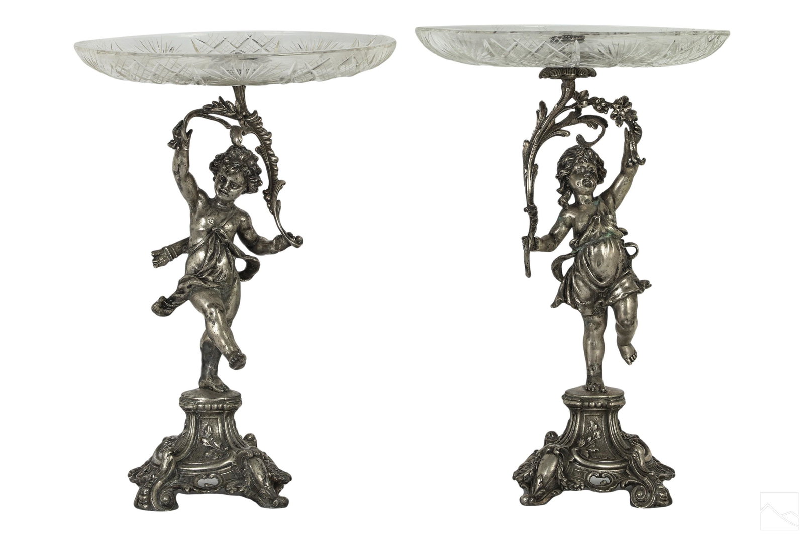 19C Antique Silverplate & Crystal Figural Compotes: A pair of antique silver plate and fine cut crystal centerpiece compotes tazza. Features semi nude putti Cupid figures holding a garland supporting a round top cut crystal dish, and surmounting a high