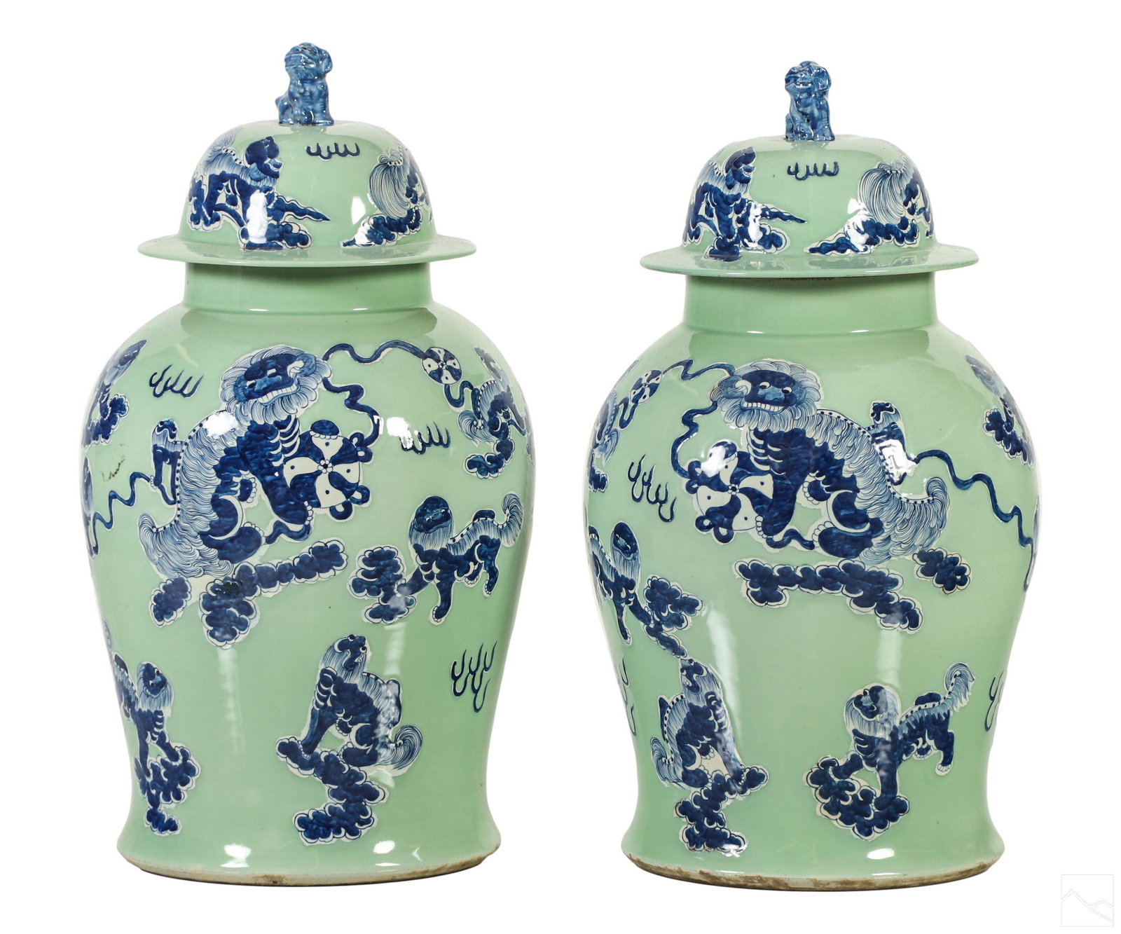 Chinese Celadon Blue White Porcelain Foo Dog Jars: A pair of Chinese porcelain lidded ginger jar lidded urns. Creamy green celadon glaze finish with rich blue and white Foo Dog guardian lion decorations. Interior glazed to bottom of neck. No apparent