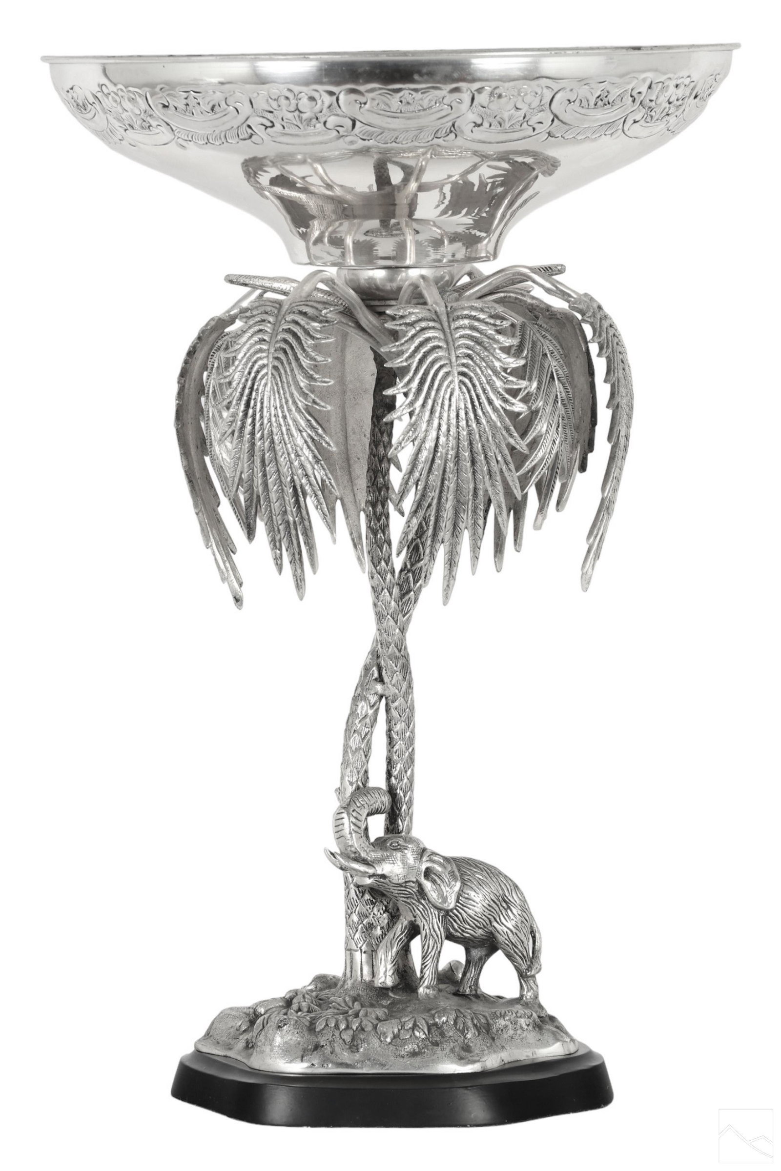 Orientalist Silverplated Elephant & Oasis Epergne: A large elaborate silver plated compote epergne centerpiece. Ornate relief to border of bowl. Striking body produced with Orientalist wildlife landscape base decorated with a twisted palm tree pedesta