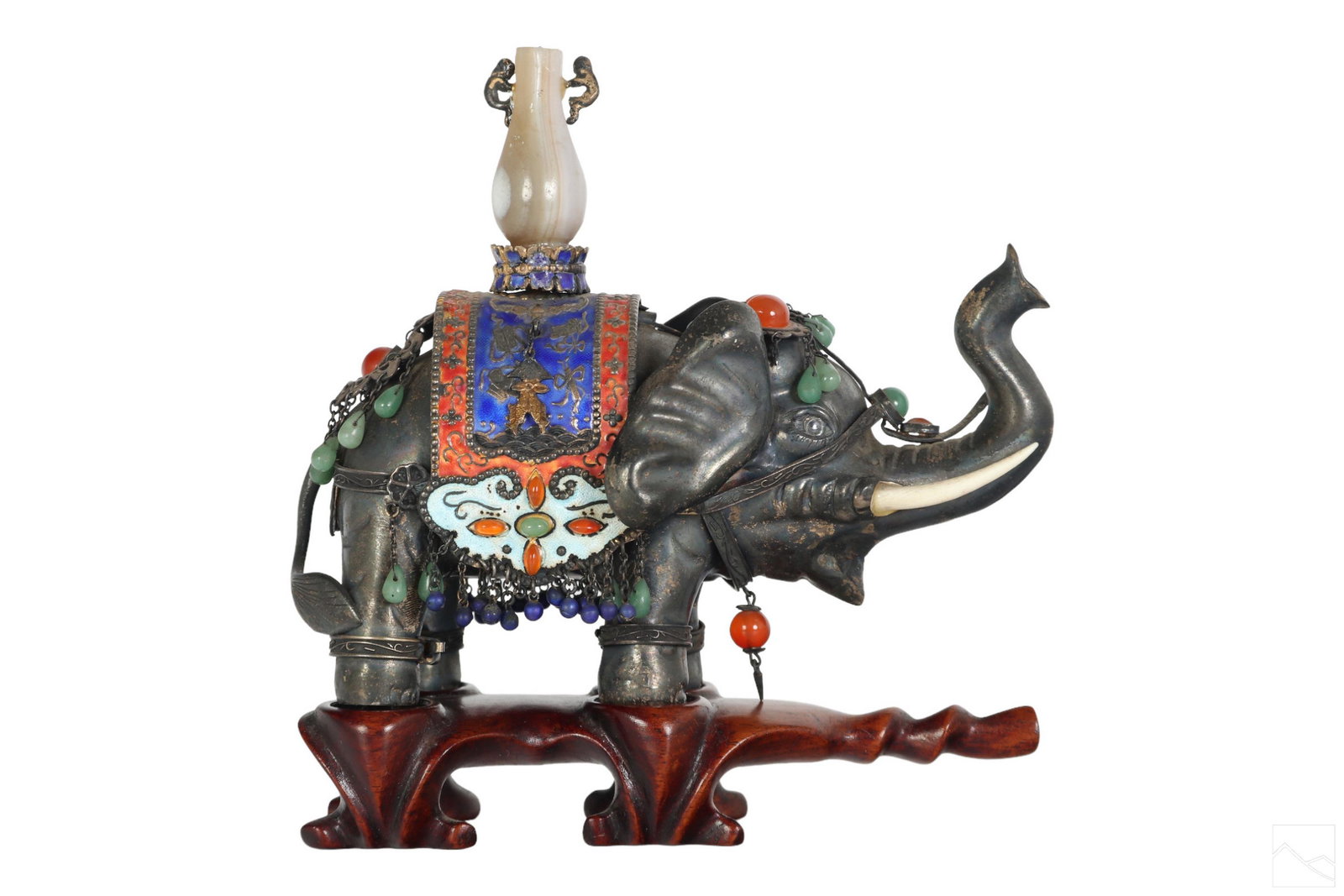 Chinese Enameled Silver & Jeweled Elephant Statue: An antique Chinese enameled silver elephant figurine. Embellished with jade, lapis, and carnelian stones with a jadestone urn shaped finial. Accompanied with fitted carved wood stand. Measures 4.75" x