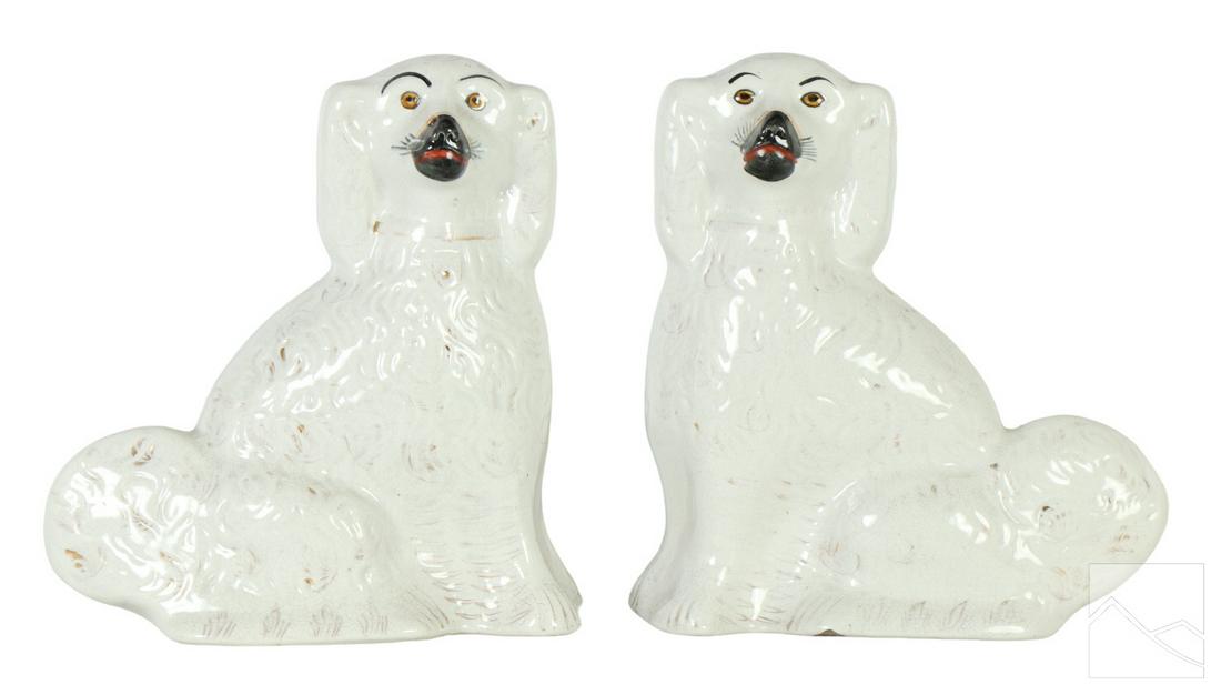 19C. Staffordshire English Porcelain Dog Figurines: A pair of antique English Staffordshire ceramic dog statues. Each classic opposing sculpture features curly hair repousse, and modeled wearing a collar, with floppy Spaniel style ears. No apparent mar