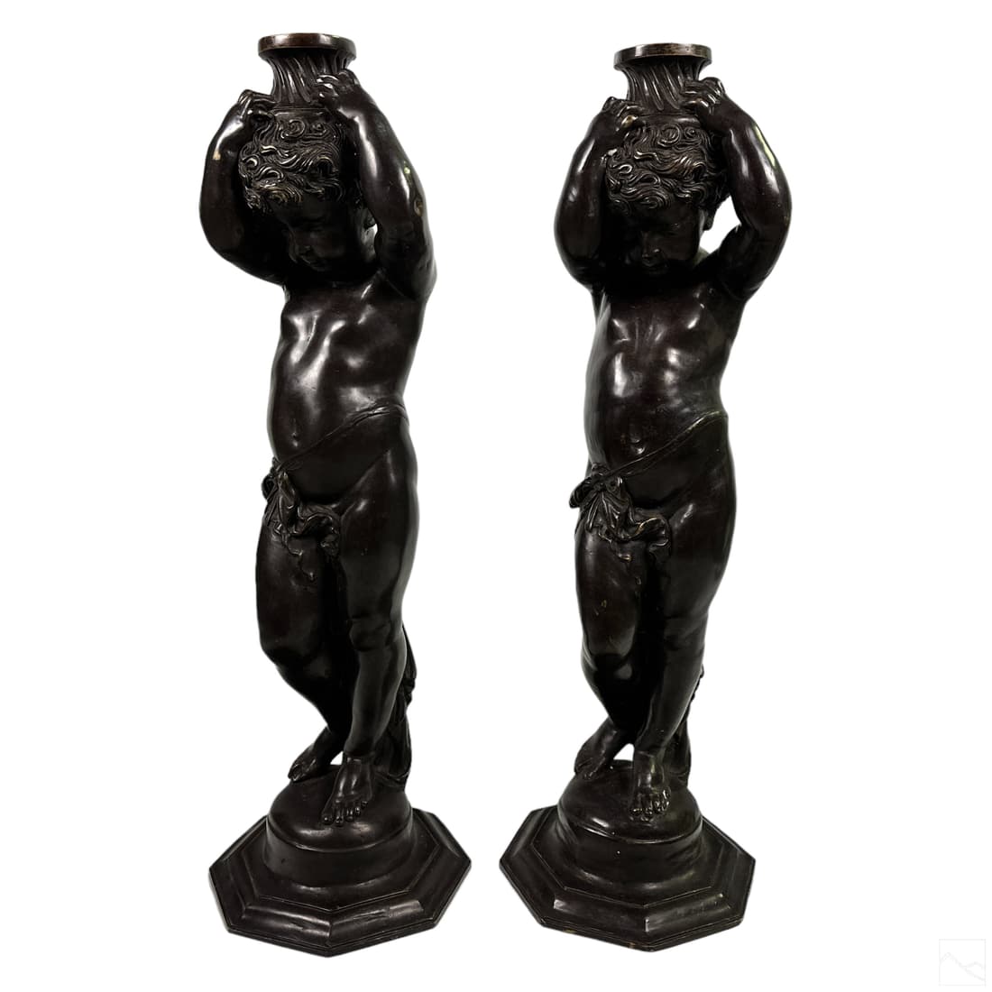 Bronze Life Size Nude Putti Plant Stand Sculptures: A pair of life sized bronze statues. Neoclassical style figural works, each depicting a semi nude putti figure holding a flattened architectural element form above his head, which serves as the platfo