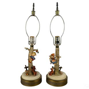 Goebel Hummel German Porcelain Pair Figural Lamps: A pair of Hummel German porcelain lamps produced by Goebel. Hand painted ceramic art pottery, with pierced bronzed metal bases. Titled, "Out of Danger." Depicting boy and girl figures, with a dog, and