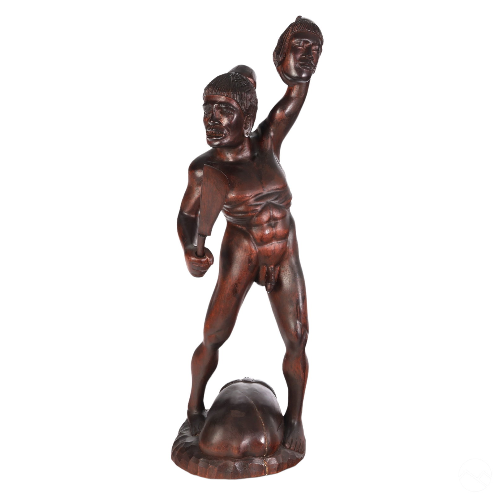 Nude Polynesian Tribal Headhunter Wood Sculpture: An artisan hand carved wooden statue. Features a primitive indigenous tribal nude male standing over torso form, holding a machete knife in one hand and a figural head aloft in the other, on emerging