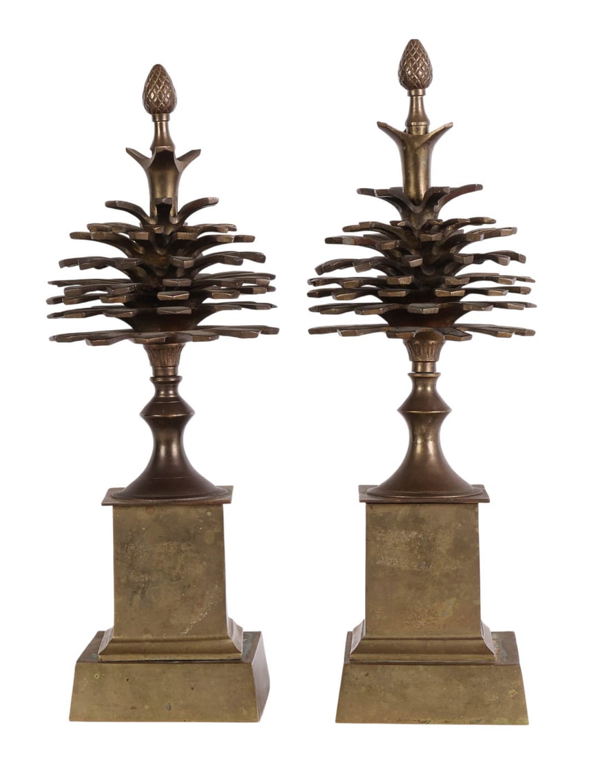 Maison Charles Pair of Brass Pinecone Garnitures: Pair of Maison Charles style brass pomme de pin pinecone garnitures. Features a squared, stepped plinth supporting a pinecone form topped with an acorn finial. The design is completed with patinated b