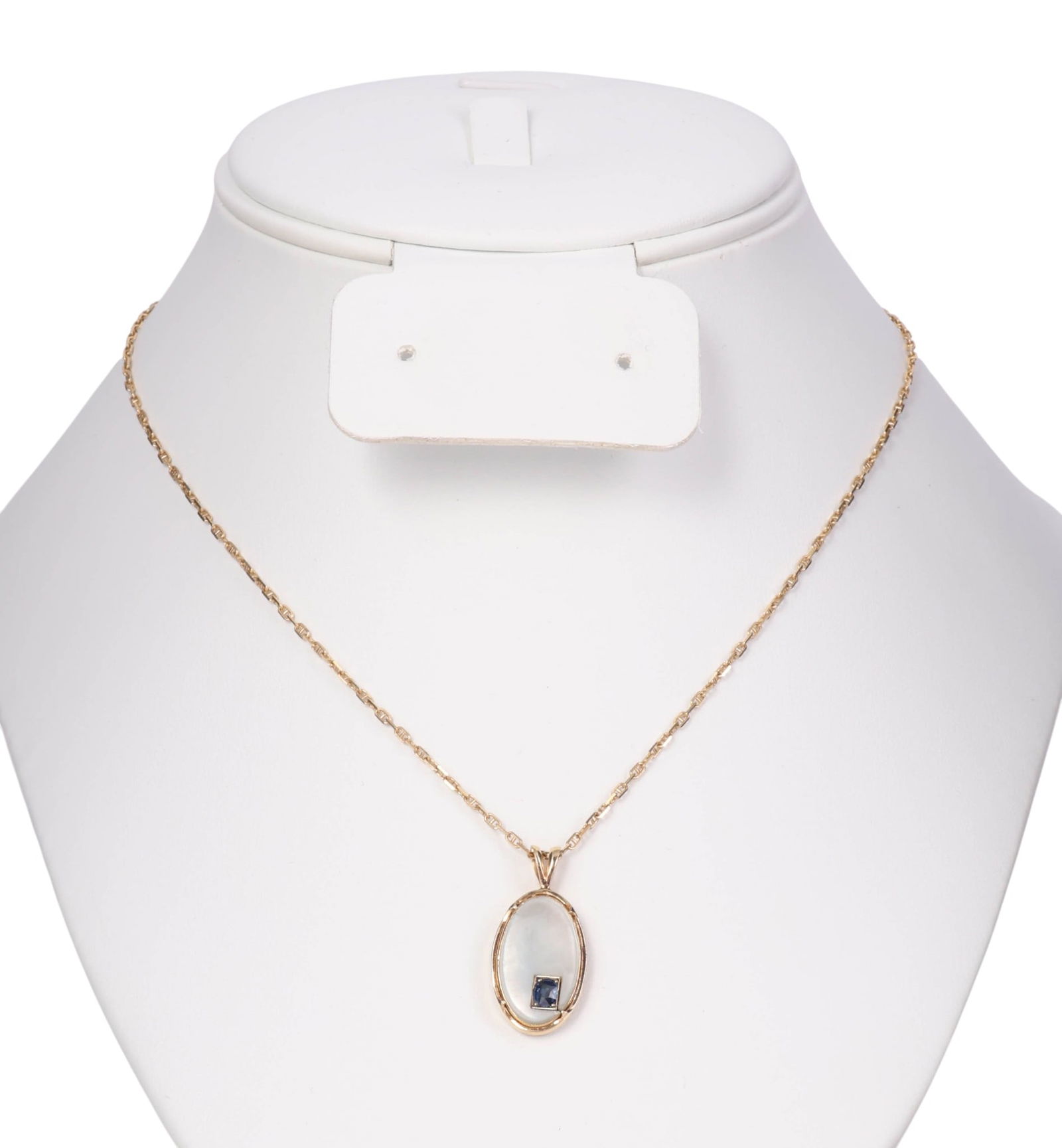 14k Gold Sapphire Mother of Pearl Pendant Necklace: Elegant pendant necklace crafted of 14k gold, featuring an oval-shaped mother-of-pearl centerpiece mounted in a polished gold bezel. The pendant is accented with a small oval faceted blue sapphire gem