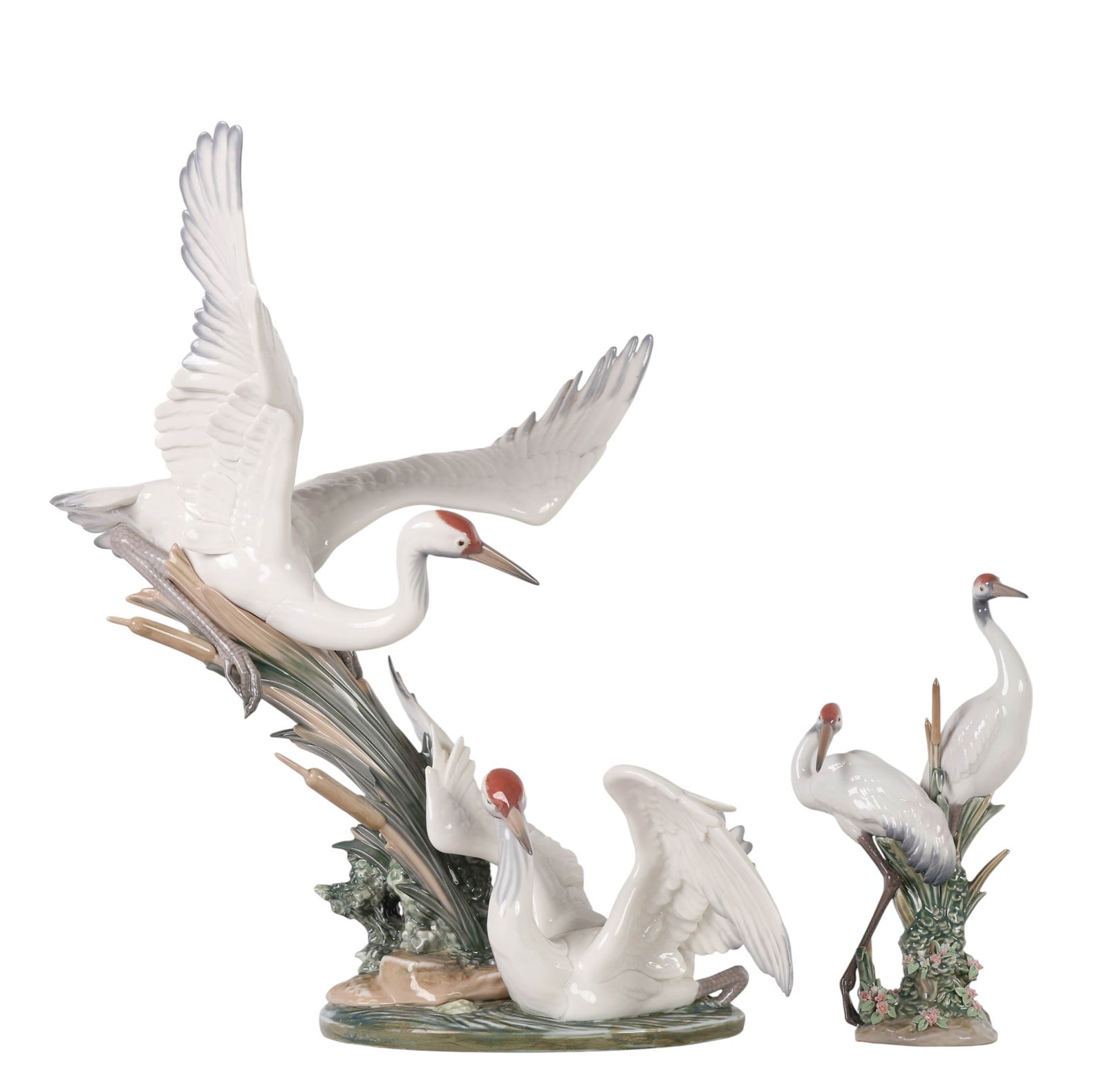 Lladro Spain Crane Bird Porcelain Figurine 2pc LOT: Two Lladro Spain porcelain sculptures designed by Salvador Debon, including Courting Cranes, model number 1611, issued in 1989 and depicting a pair of cranes standing among cattails and blossoms, and