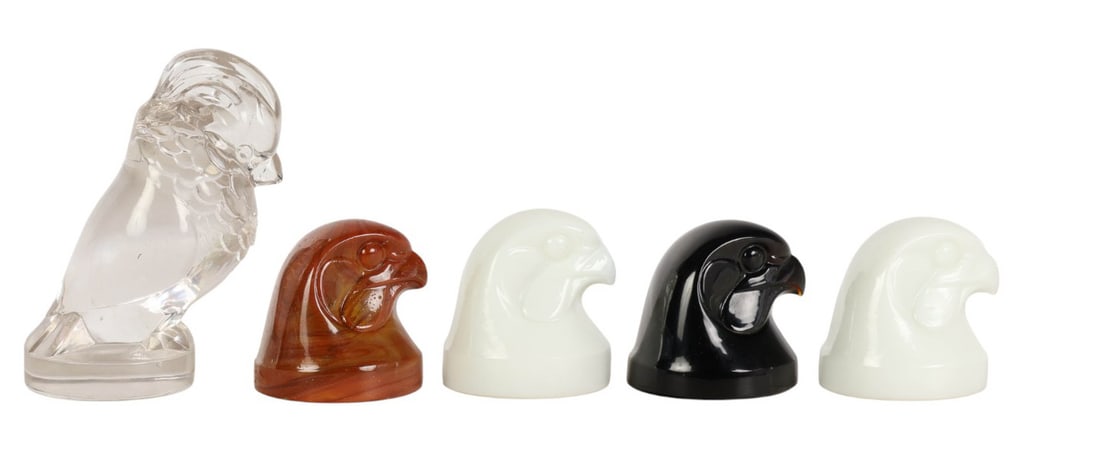 Glass Falcon Eagle Head Paperweight Hood Ornaments: Molded glass figures in the form of of birds of prey examples. Varied colors and finishes. The clear glass piece impressed with the word M Model. Measurements range from approximately 2.5" x 2.75" x