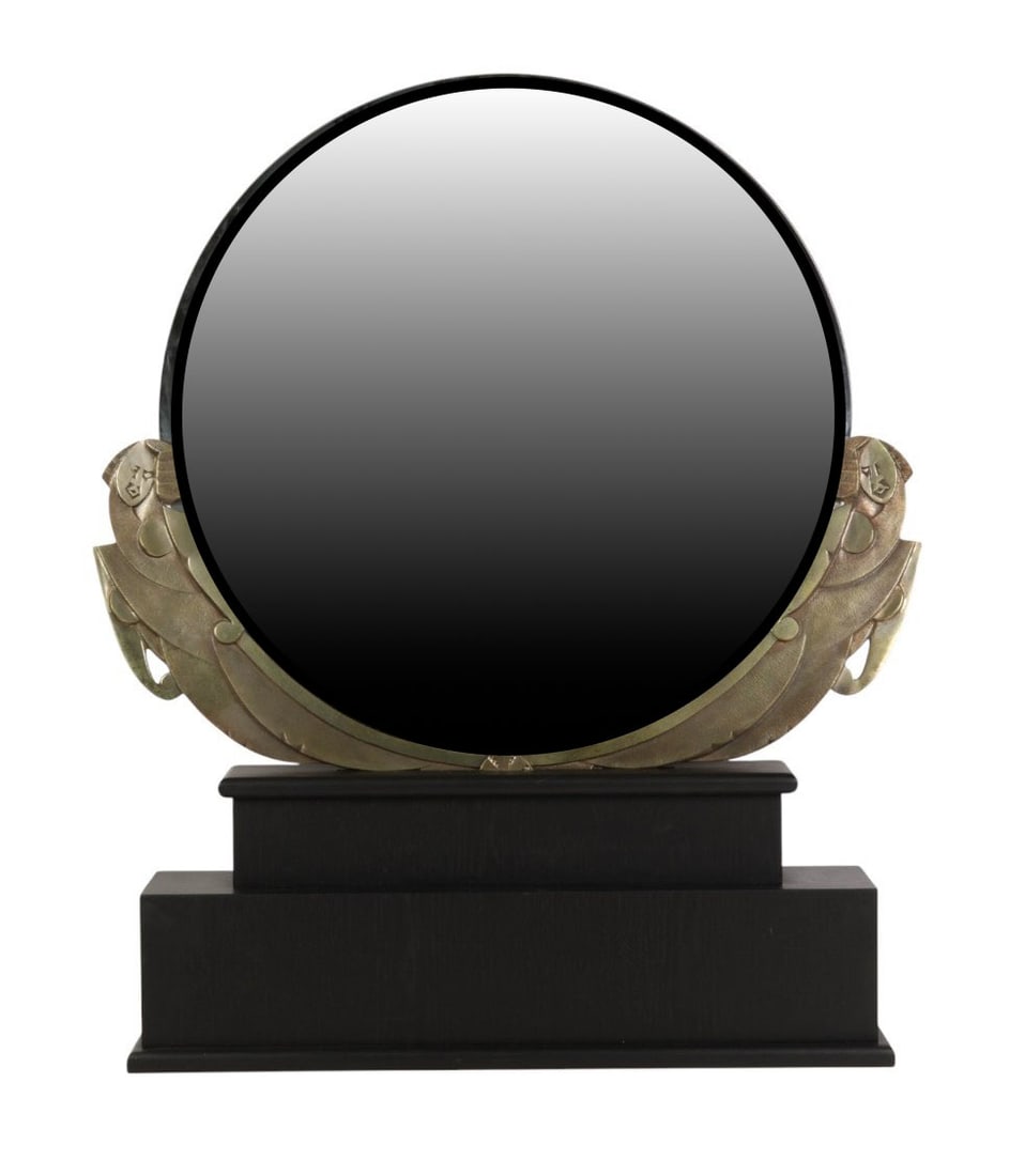 French Art Deco Bronze Figural Table Top Mirror: French Art Deco period round tabletop mirror set within a cast bronze frame, mounted on a stepped rectangular dark wood base. The bronze frame is adorned with stylized geometric female figures on each