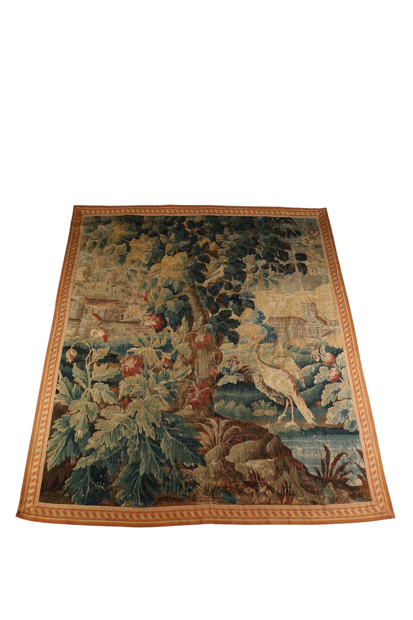 Antique Woodland Landscape w/ Bird Woven Tapestry: Antique woven textile showcasing a landscape with a large central tree, foliage, and a bird standing beside a stream. Architectural structures appear in the background, having a diagonal striped