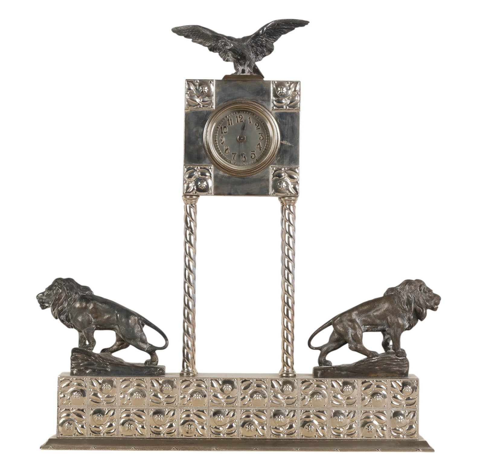 Austrian Secessionist Silvered Lion & Eagle Clock: Austrian Secessionist silver plated mantel clock featuring a square clock case supported by twisted columnar supports and surmounted by a spread wing eagle finial. The base is decorated with repousse 