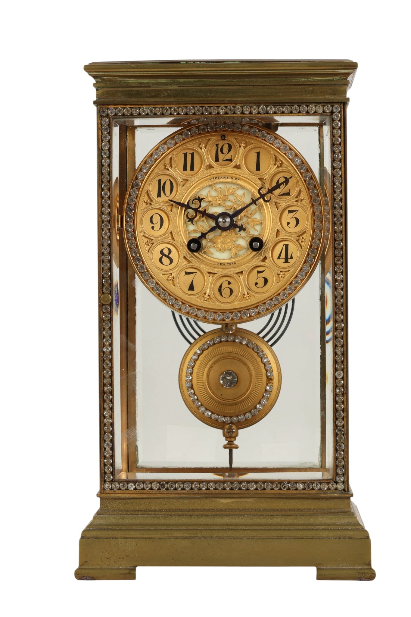 Tiffany & Co. Jeweled Brass and Glass Mantel Clock: Antique Tiffany and Company jeweled brass and glass mantel clock featuring a rectangular case with beveled glass panels and a gilt brass frame adorned with decorative crystal accents. The ornate dial 
