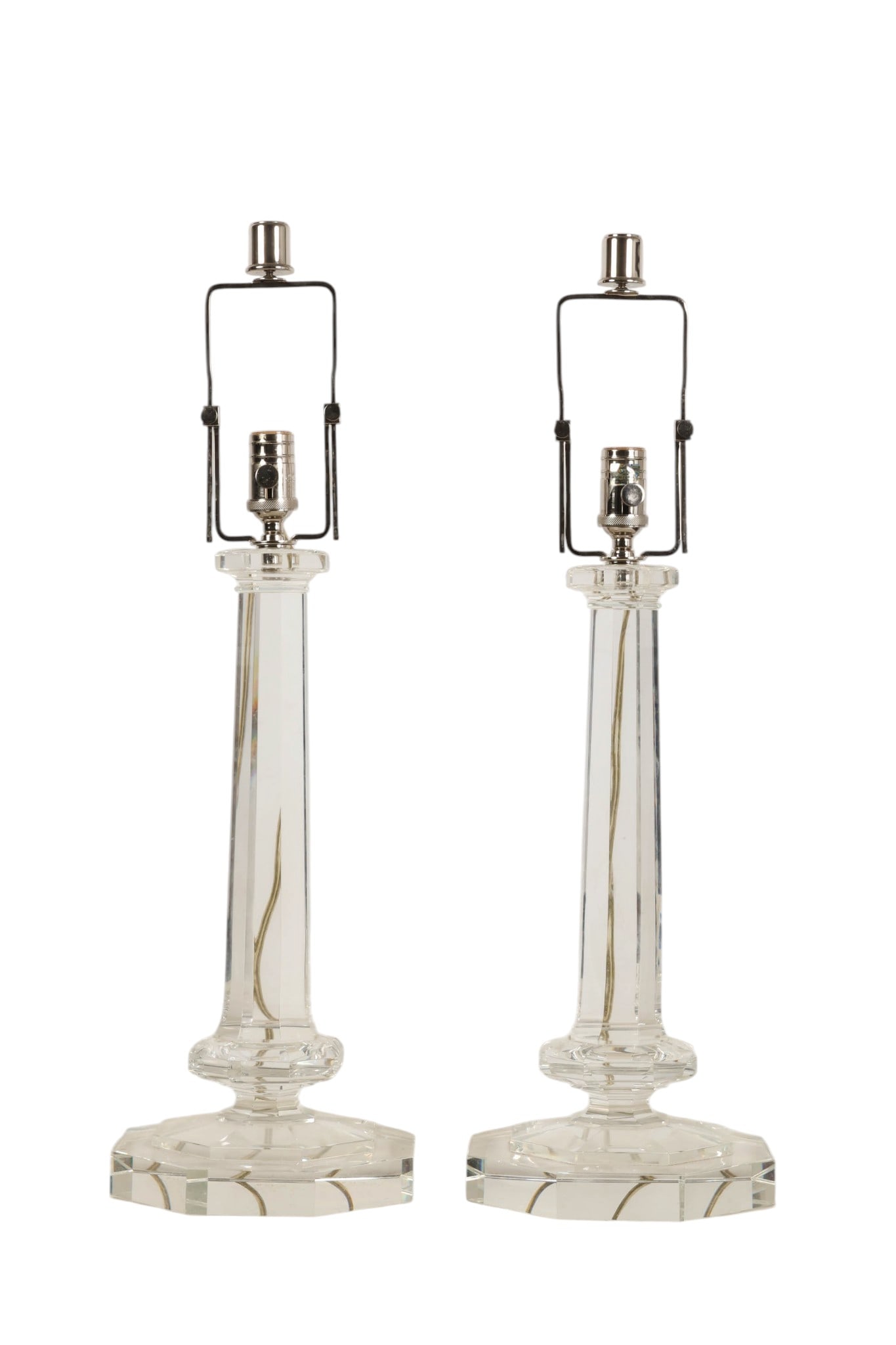 Solid Clear Glass Hollywood Regency Pair of Lamps: Pair of Hollywood Regency style cut glass table lamps featuring tall faceted columnar bodies rising from stepped octagonal bases. The clear glass construction creates strong light refraction and prism