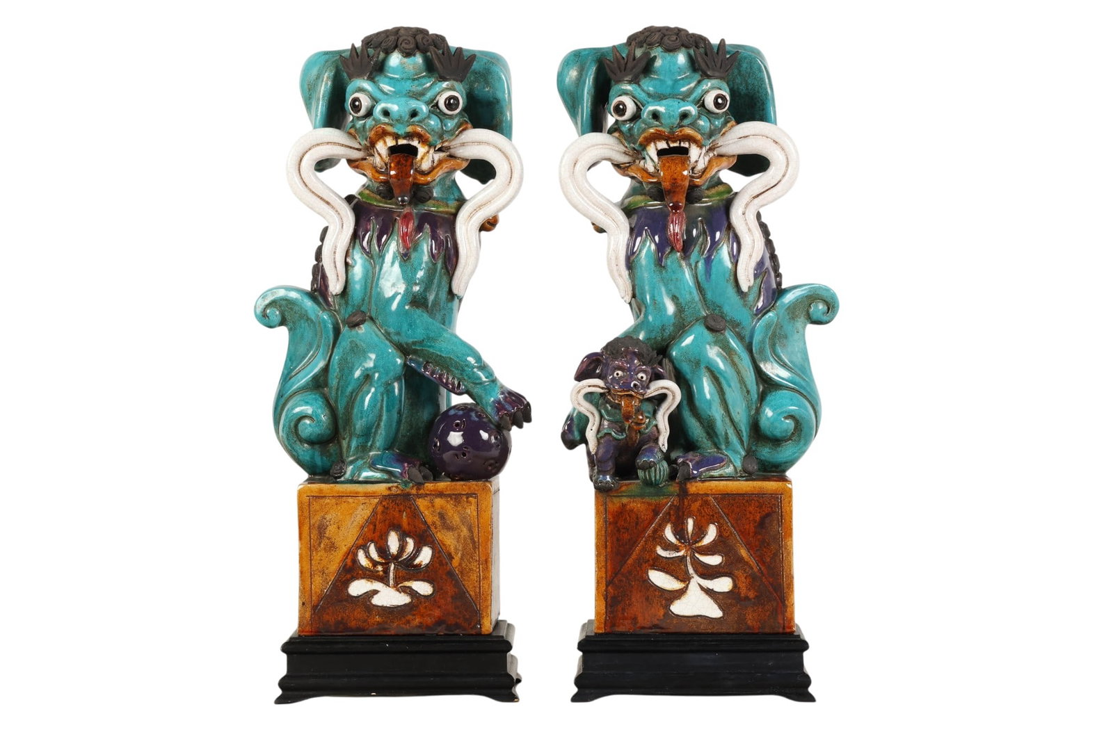 Chinese Pair of Glazed Pottery Guardian Sculptures: Pair of Chinese glazed pottery foo dog figures modeled in seated form with expressive facial features bulging eyes and stylized curling manes. Each figure is adorned with flowing ribbon and collar det