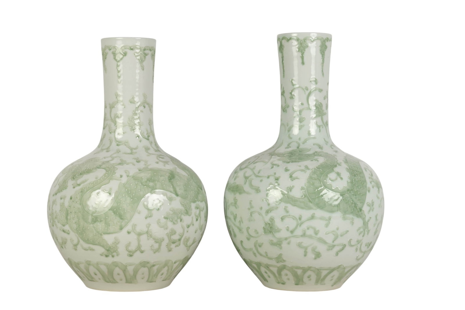 Chinese Pair of Celadon Glazed Dragon Relief Vases: Pair of Chinese porcelain celadon glazed baluster form vases featuring raised relief decoration of dragons amid scrolling clouds. Each vase displays a pale green celadon glaze over a white ground with