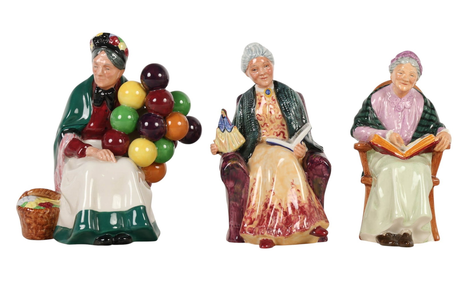 Royal Doulton Old Balloon Seller Family Album LOT: Royal Doulton England porcelain figurines, lot of three. Includes Prized Possessions HN2942 (1982-1982). Designed by Robert Tabbenor. Family Album HN2321. (1966-1973). Designed by Mary Nicoll. The Old