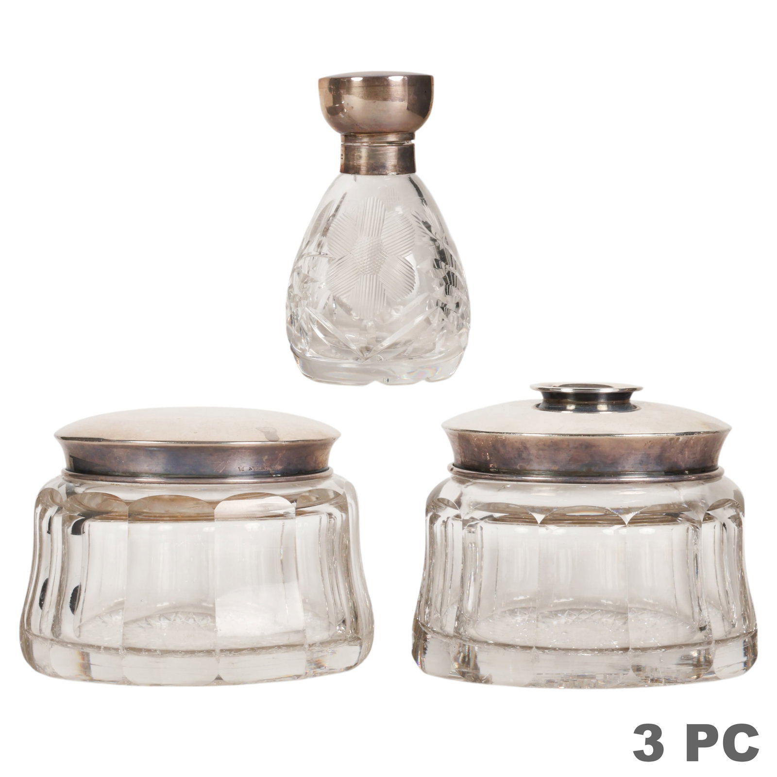 Silver Mounted Crystal Vanity Dresser Jars 3pc LOT: Three-piece vanity lot comprising two cut crystal dresser jars with silver-mounted lids and a cut crystal cologne bottle with hinged silver-mounted cap. Crystal bodies feature geometric and foliate cu