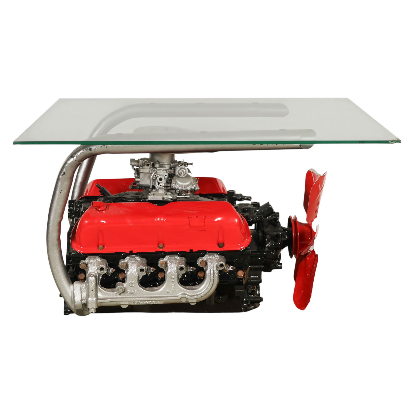 Ford Motor V8 Engine Block Glass Top Coffee Table: Custom coffee table crafted from a Ford V8 engine block, mounted within a welded steel frame and topped with a fitted glass surface. This bespoke, one-of-a-kind piece features red Ford branded valve c