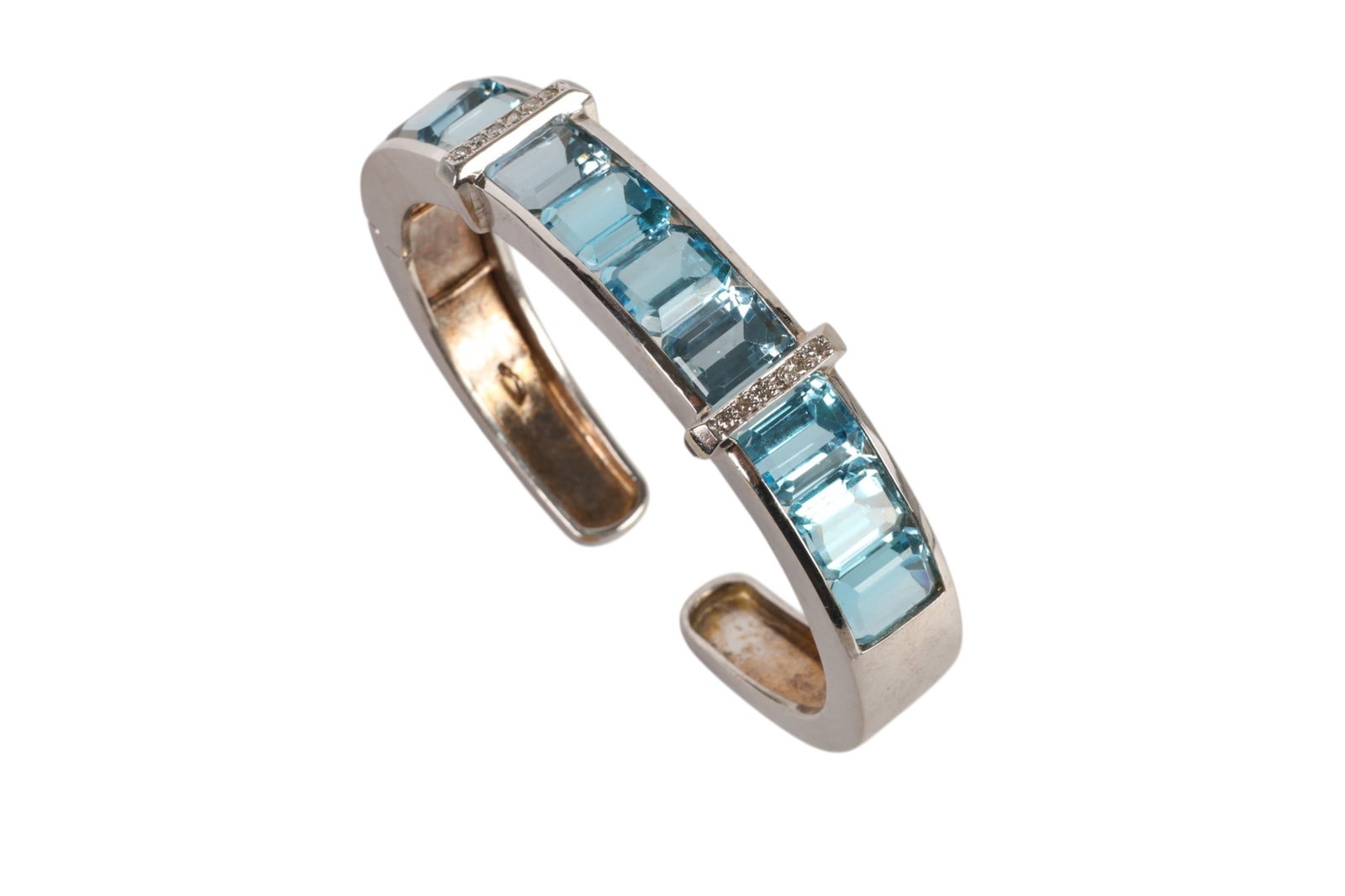 14k White Gold Diamond Topaz Hinged Cuff Bracelet: 14K white gold, a hinged cuff bracelet set with ten emerald cut blue topaz gemstones totaling approximately 38 carats accented by small round cut diamonds with a total approximate weight of 0.40 carat